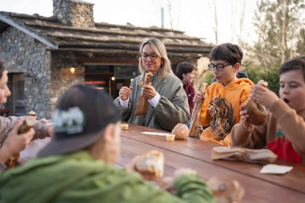 Familie mit Kindern genießt gemeinsam Brotzeit im Freien – nachhaltige Ernährung und gemeinsames Essen in natürlicher Umgebung.